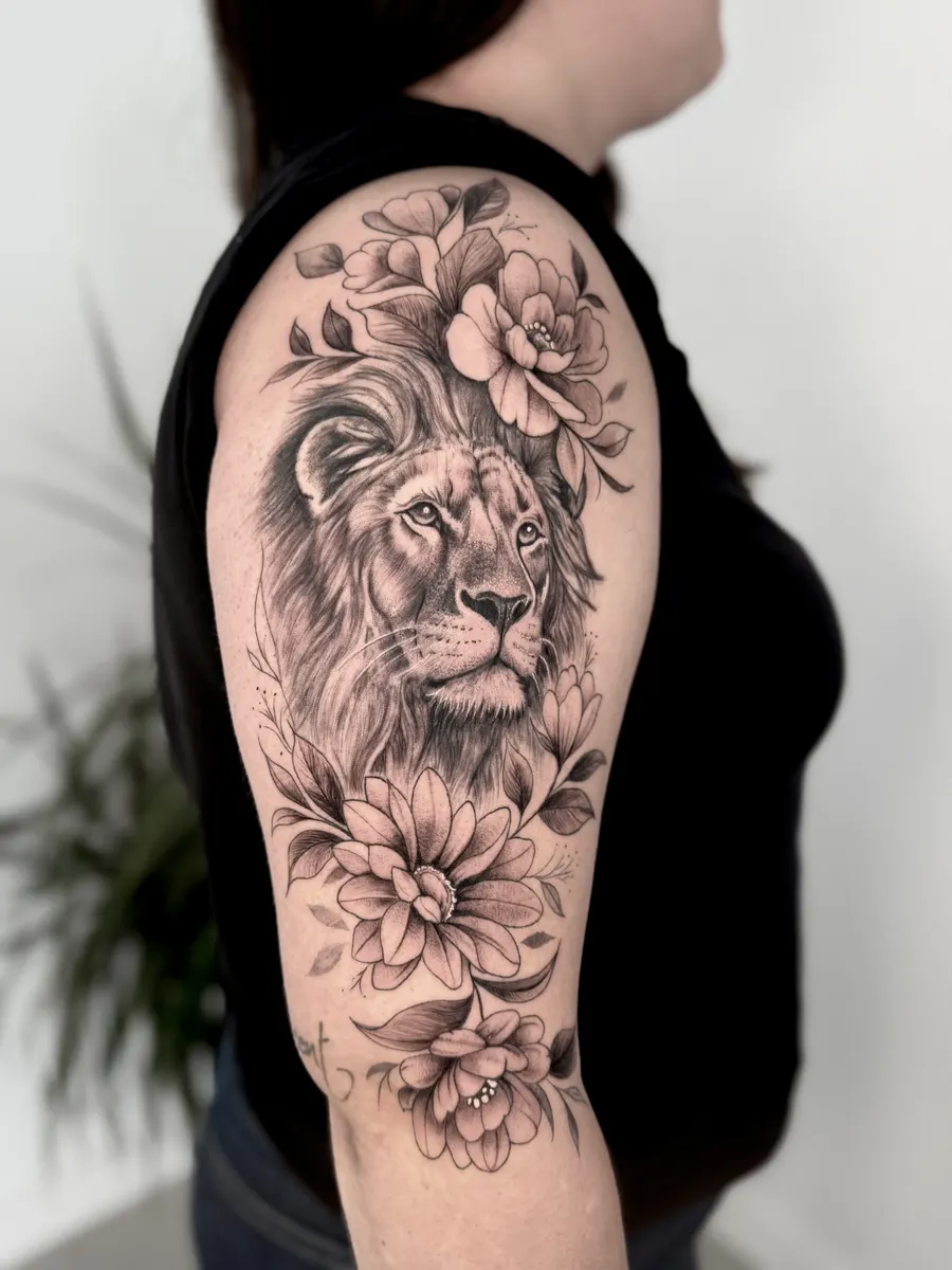Cabeza de león en realismo rodeada de flores en línea fina, tatuada en medio brazo